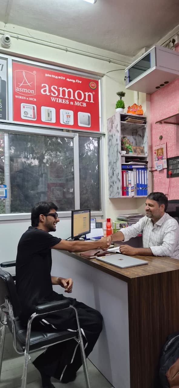 Narayan Mali shaking hands with Kundan Khatri across the shop counter